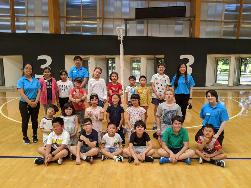 Group of PIEX kids and teachers in a basketball court